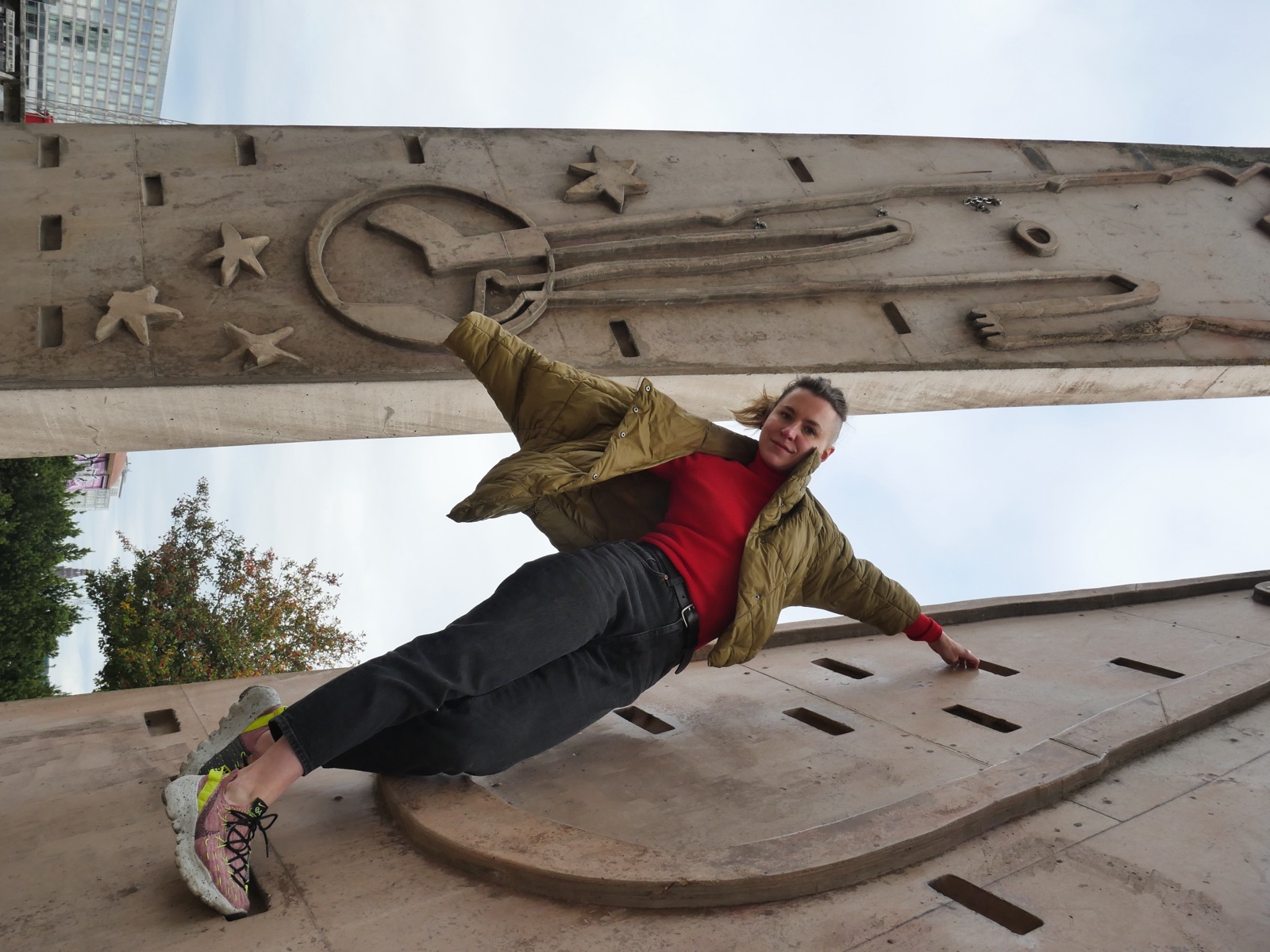 Julia bridging between two brutalist concrete pillars carved with reliefs